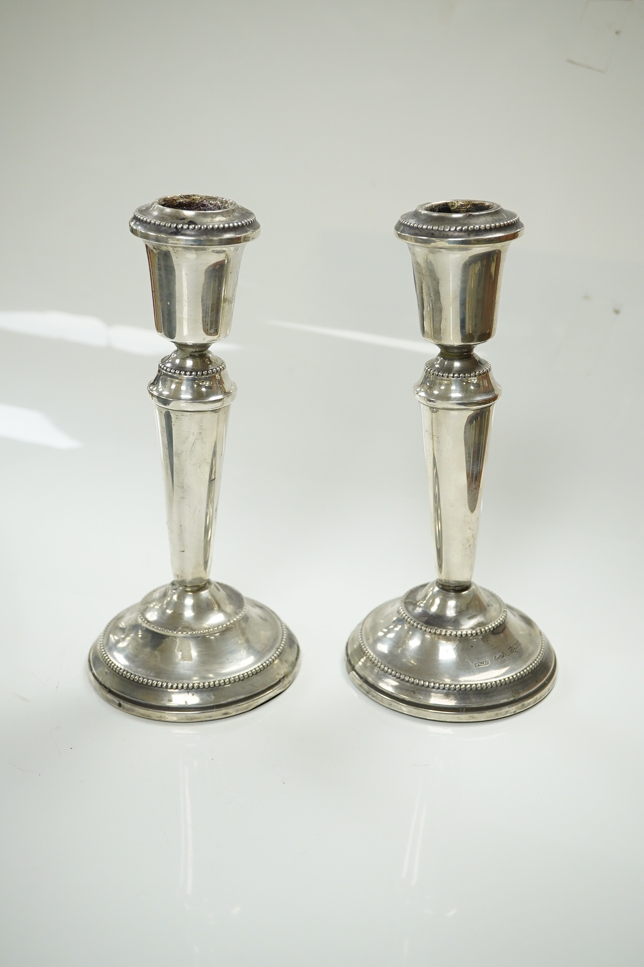 A pair of modern loaded silver candlesticks, 18cm high, an embossed silver mounted photograph frame, 20cm and a plain rectangular photograph frame, 16cm. Condition - fair to good